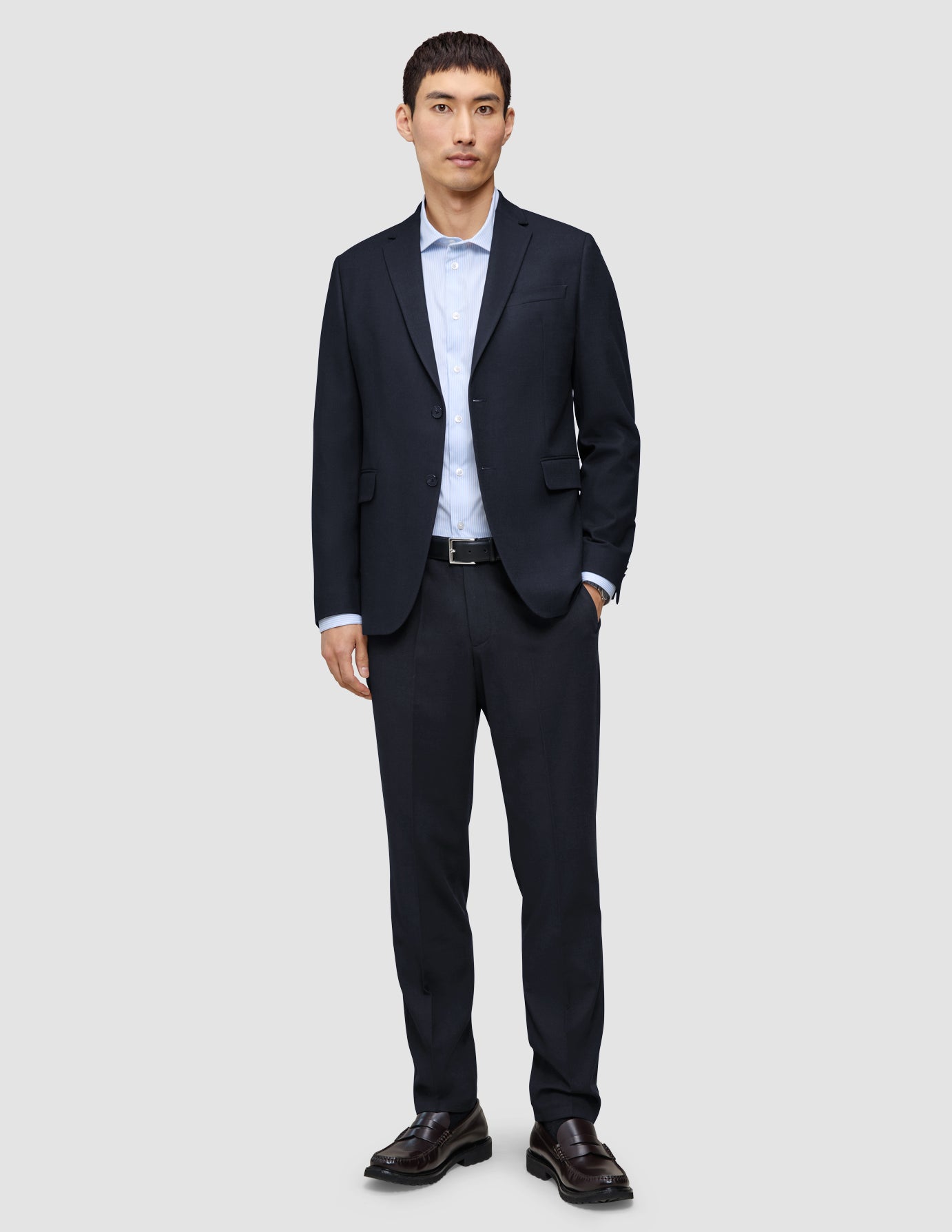 En mand iført en Motion Blazer Slim i farven Midnight Blue, en lyseblå skjorte og mørke læderloafers.
